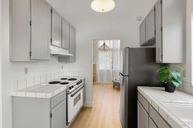 a kitchen with stainless steel appliances a sink a refrigerator a stove a oven a chimney and cabinets