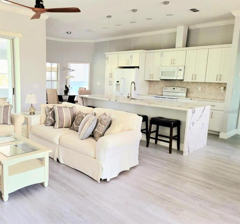 1415 Beach Club Lane Apollo Beach, FL 33572 - Photo 5 of 20 a large white open kitchen with white cabinets and stainless steel appliances