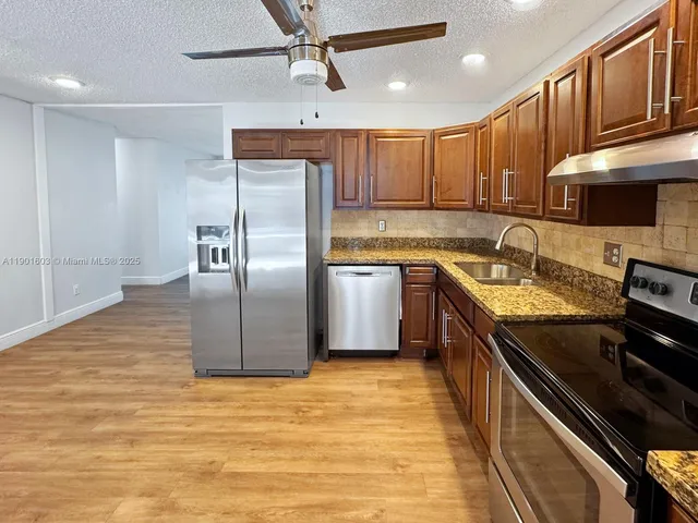 a kitchen with stainless steel appliances granite countertop a sink a stove and a refrigerator