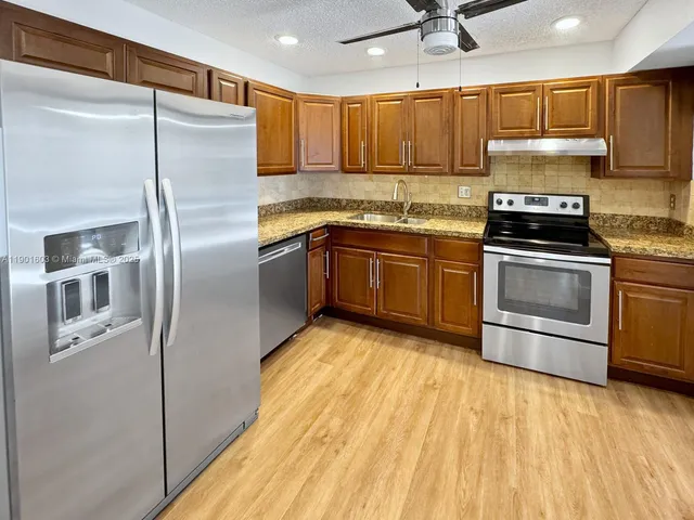 a kitchen with stainless steel appliances granite countertop a refrigerator a sink and a stove
