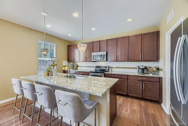 a kitchen with stainless steel appliances granite countertop a stove a sink a microwave a island with a dining table and chairs