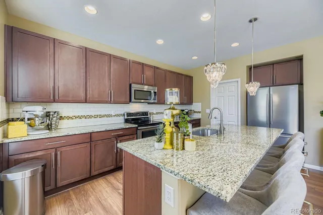 a kitchen with kitchen island granite countertop a sink cabinets and stainless steel appliances