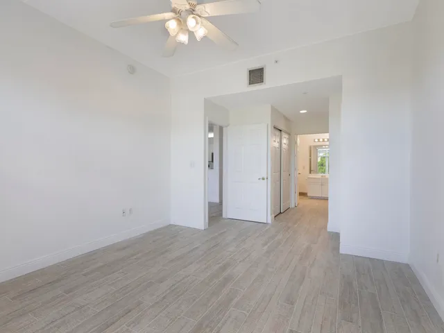 an empty room with wooden floor and a chandelier fan