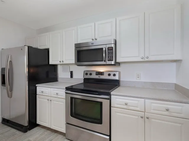 a kitchen with white cabinets and stainless steel appliances
