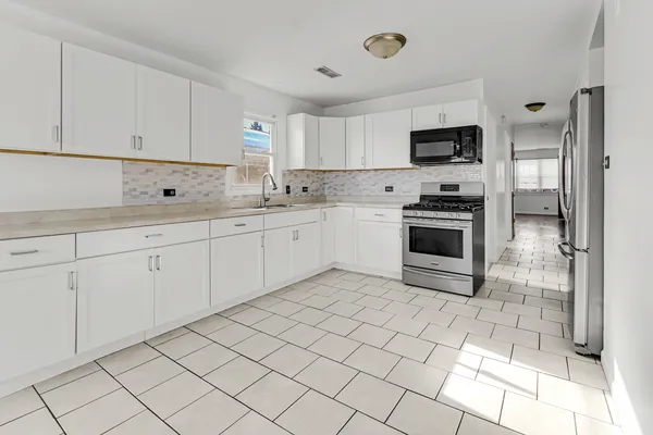 a kitchen with white cabinets a sink and white appliances