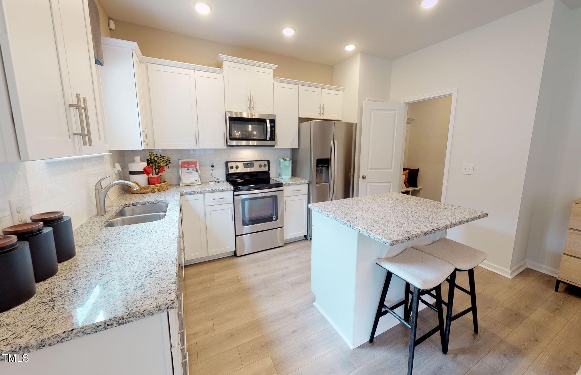 1105 Freestone Road Durham, NC 27703 - Photo 3 of 21 a kitchen with stainless steel appliances granite countertop a stove a sink a microwave a refrigerator and white cabinets