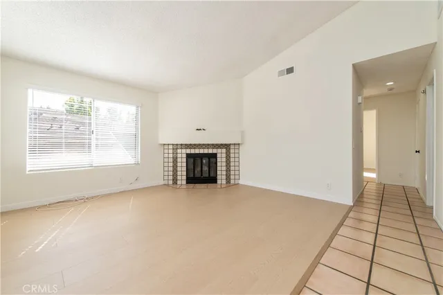an empty room with windows and fireplace