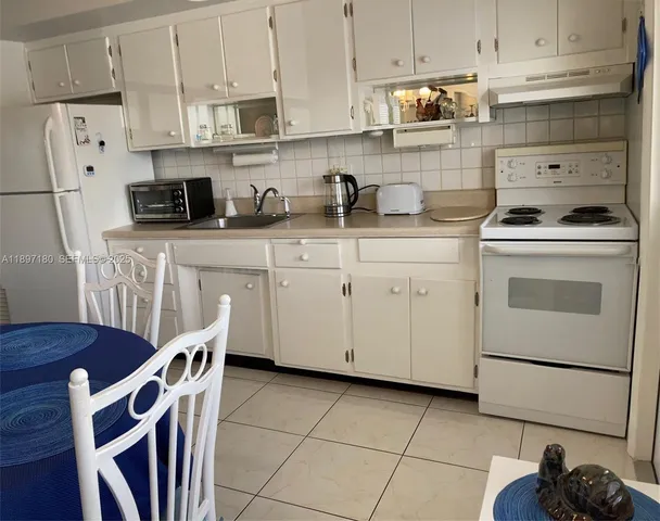 a kitchen with stainless steel appliances granite countertop a sink stove a refrigerator and white cabinets