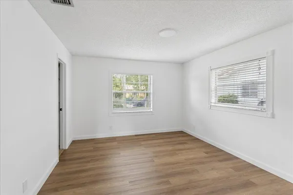 an empty room with wooden floor and windows