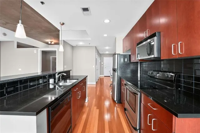 a kitchen with stainless steel appliances granite countertop a sink a stove and a wooden cabinets