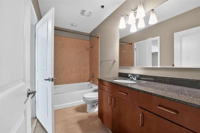 a bathroom with a granite countertop sink a toilet a mirror a bathtub and shower