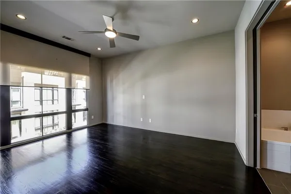 an empty room with wooden floor fan and windows