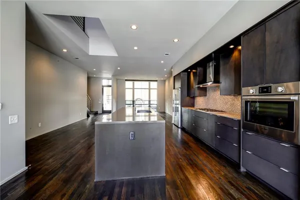 a large kitchen with stainless steel appliances wooden floor and a large window