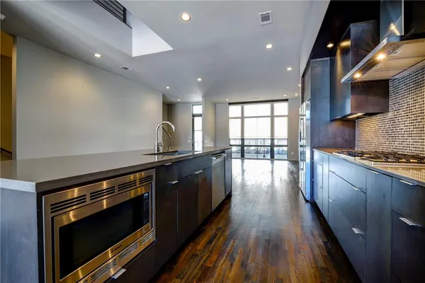 a open kitchen with stainless steel appliances granite countertop a stove and a wooden floors