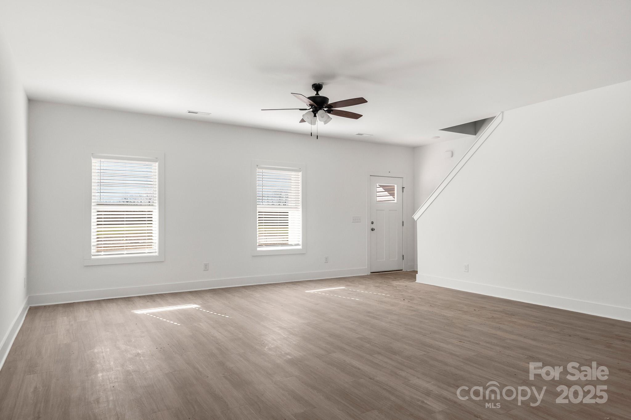 3307 Old Pageland Monroe Road Monroe, NC 28112 - Photo 2 of 35 an empty room with wooden floor ceiling fan and windows