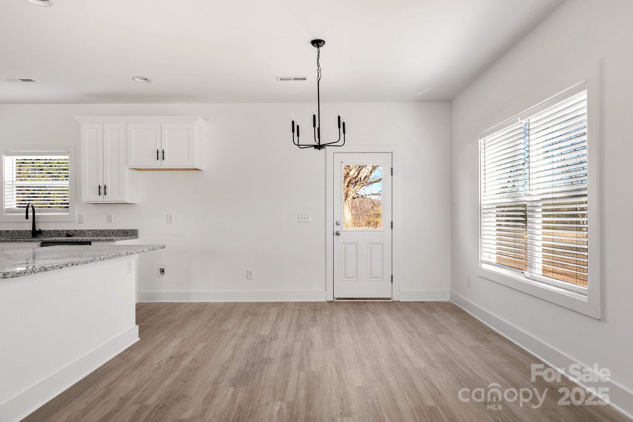 3307 Old Pageland Monroe Road Monroe, NC 28112 - Photo 7 of 35 a kitchen with granite countertop a stove a sink and white cabinets with wooden floor