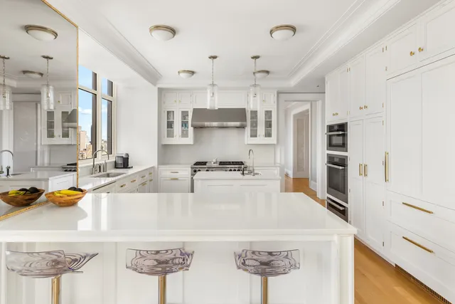 a large white kitchen with a large window a sink and stainless steel appliances