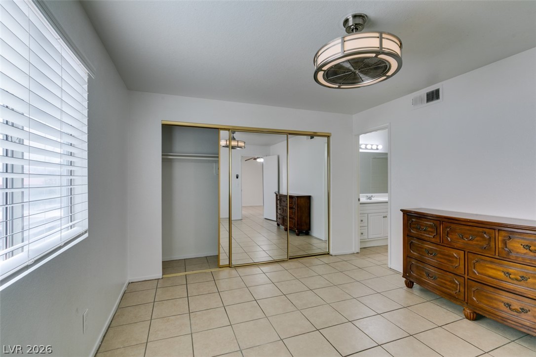 7570 West Flamingo Road, Unit 252 Las Vegas, NV 89147 - Photo 34 of 44 A primary bedroom with easy-to-maintain tile flooring and a mirrored closet, leading into a private bath.