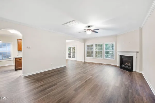 an empty room with wooden floor fireplace and windows