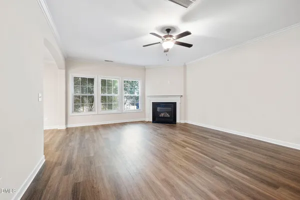 an empty room with wooden floor fan and windows