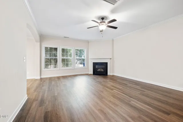an empty room with wooden floor fan and windows