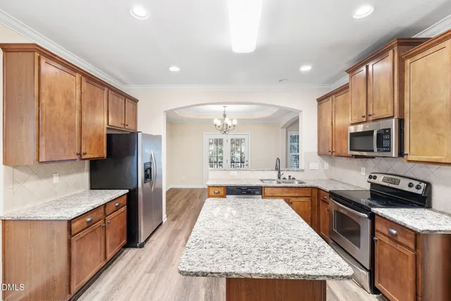 a kitchen with stainless steel appliances granite countertop a stove top oven a sink dishwasher a microwave oven and a refrigerator with wooden cabinets