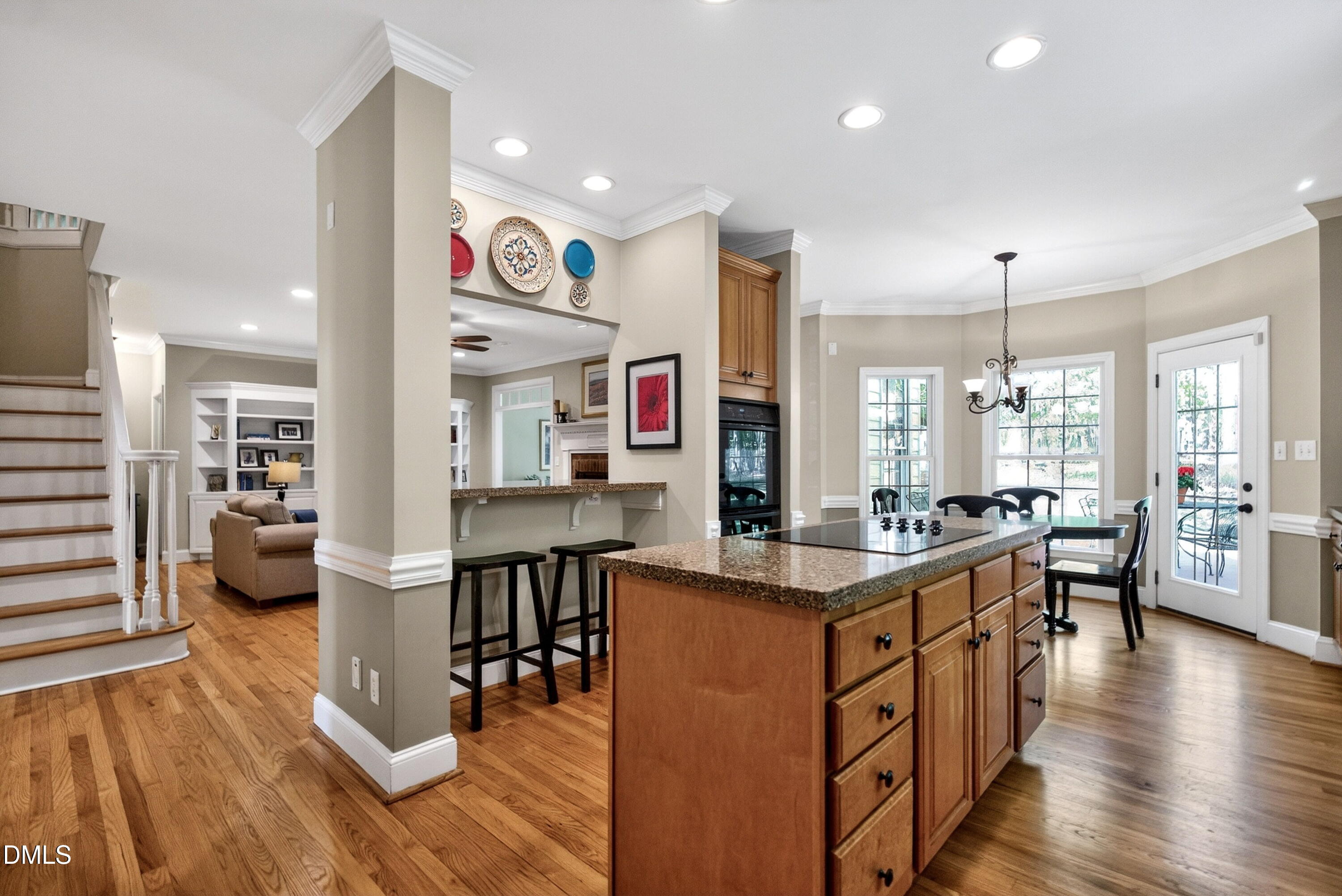 6329 Battleview Drive Raleigh, NC 27613 - Photo 13 of 36 a kitchen with stainless steel appliances kitchen island granite countertop a stove a refrigerator a dining table and chairs with wooden floor