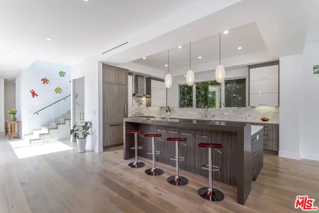 a kitchen with stainless steel appliances a kitchen island hardwood floor and a sink