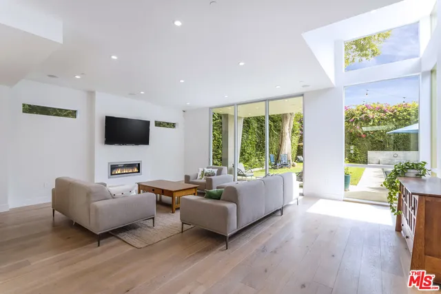 a living room with furniture flat screen tv and a large window