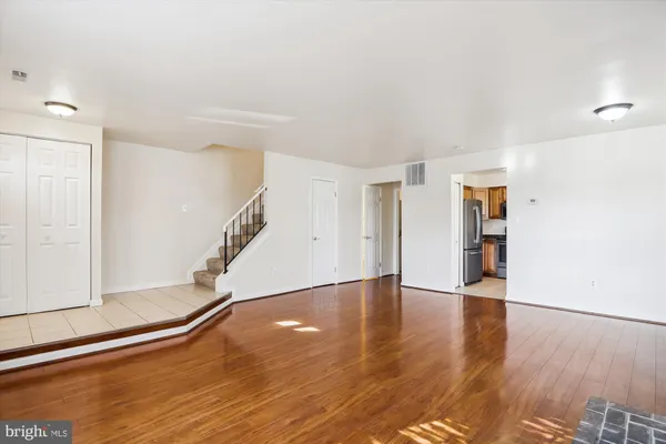 a view of an empty room with wooden floor and stairs