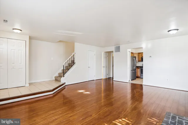 a view of an empty room with wooden floor and stairs