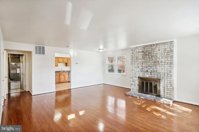 an empty room with wooden floor fireplace and windows