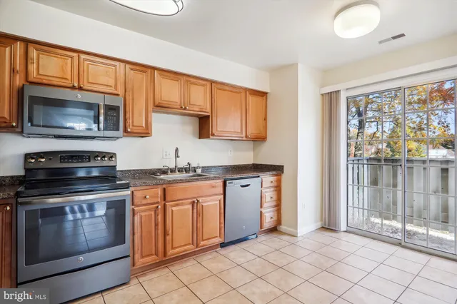 a kitchen with granite countertop cabinets stainless steel appliances and a window