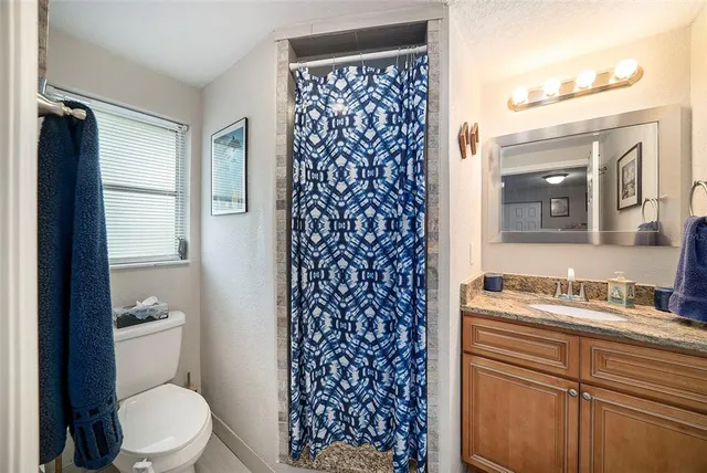 a bathroom with a granite countertop sink toilet and shower