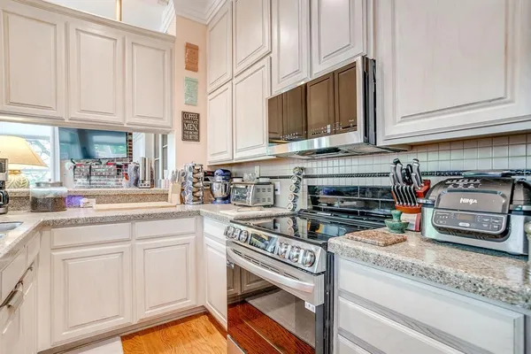 a kitchen with stainless steel appliances granite countertop a stove a sink and a white cabinets