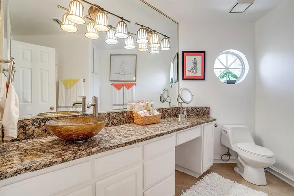a bathroom with a granite countertop toilet sink and mirror