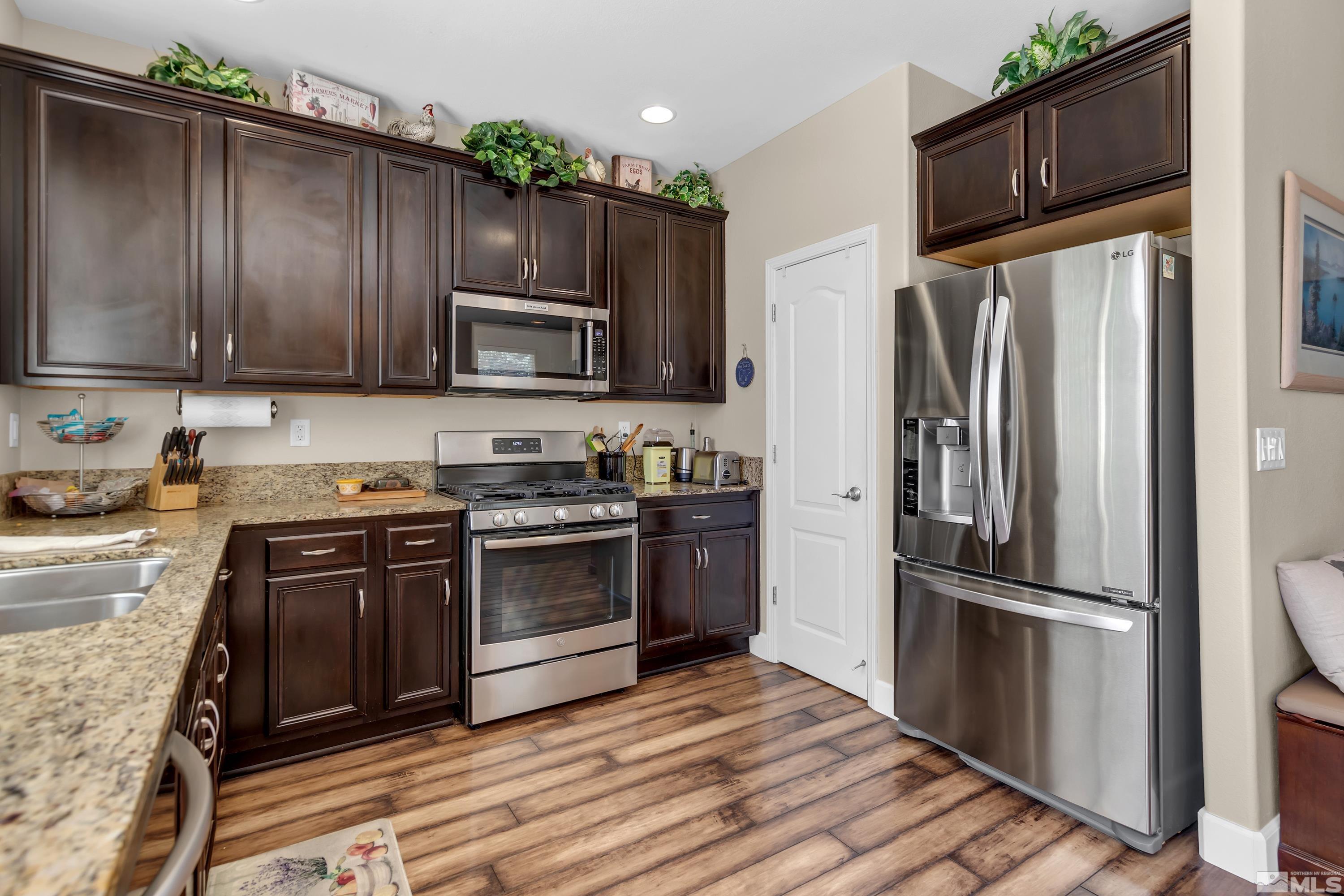 420 Manciano Way Reno, NV 89521 - Photo 12 of 30 a kitchen with granite countertop wooden cabinets a stove top oven and stainless steel appliances