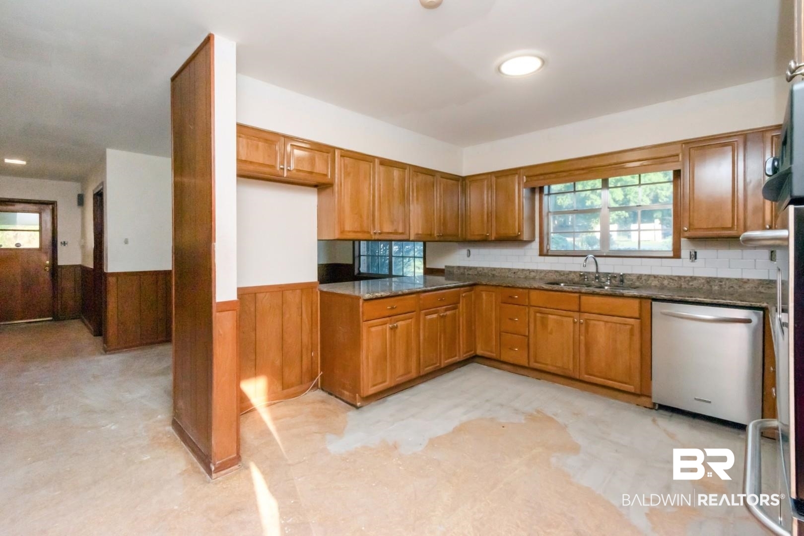 241 Suzanne Circle Mobile, AL 36608 - Photo 11 of 41 Kitchen featuring brown cabinets, a wainscoted wall, dishwasher, dark stone counters, and wooden walls