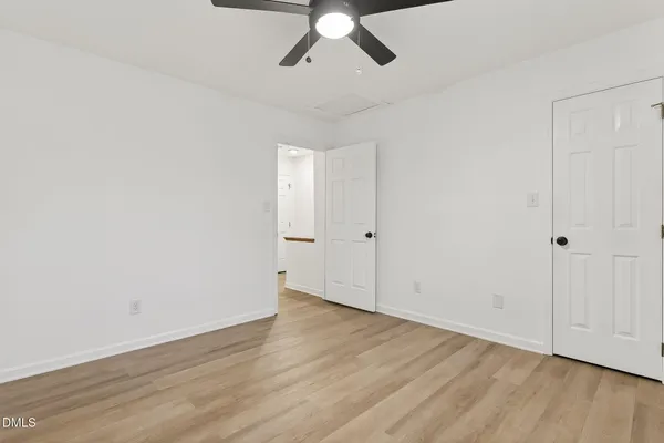 an empty room with wooden floor chandelier fan and windows