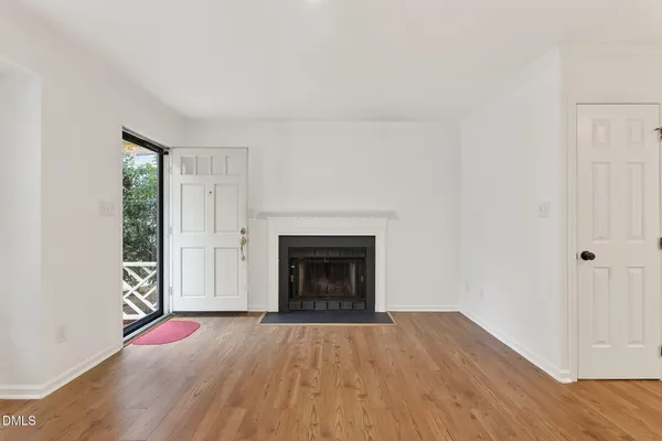 an empty room with wooden floor fireplace and windows