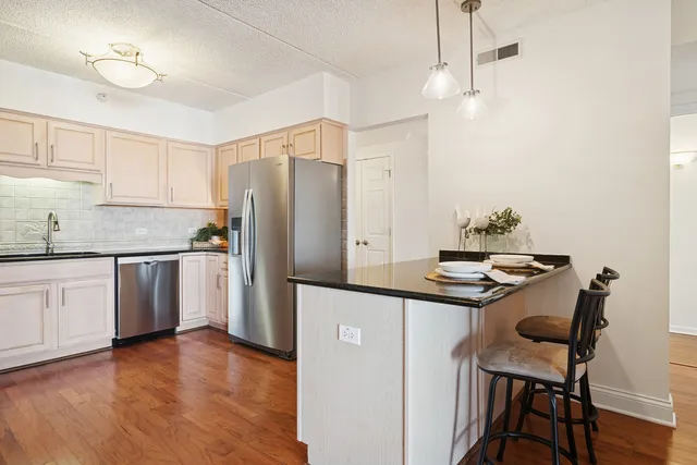 a kitchen with kitchen island granite countertop a sink cabinets and stainless steel appliances