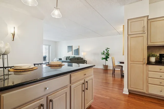 a kitchen with stainless steel appliances granite countertop a refrigerator a stove a sink dishwasher and white cabinets with wooden floor