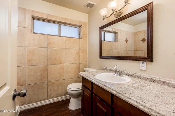 a bathroom with a granite countertop sink a toilet and mirror