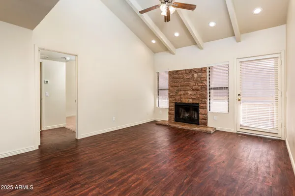 a view of an empty room with wooden floor fireplace and a window
