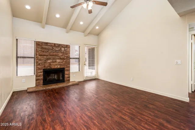 an empty room with wooden floor fireplace and windows
