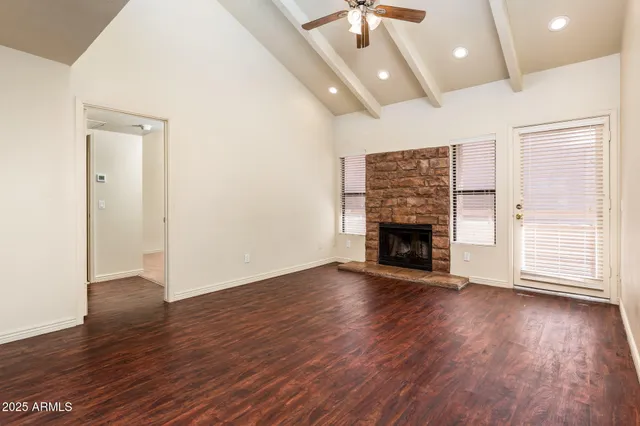 a view of an empty room with wooden floor fireplace and a window