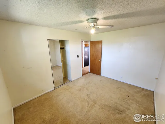 an empty room with a chandelier fan and closet