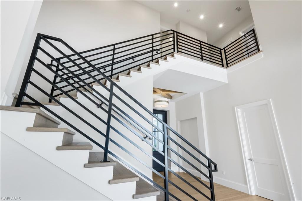 16728 Enclave Circle Naples, FL 34110 - Photo 26 of 49 Staircase featuring wood finished floors and a high ceiling