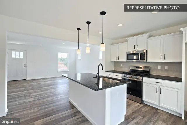 a kitchen with granite countertop a sink a counter space appliances and cabinets