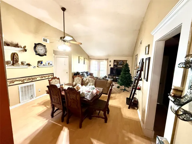 a view of a dining room and livingroom with furniture wooden floor a rug a flat screen tv a rug and a chandelier